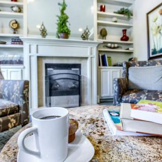A cozy living room with a cup of coffee and books on the table in front of a fireplace.