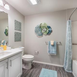 A modern bathroom with stylish decor, featuring a shower curtain, wall art, and neatly arranged towels.