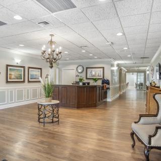 A spacious lobby area with a wooden reception desk, chandelier, and elegant furnishings.