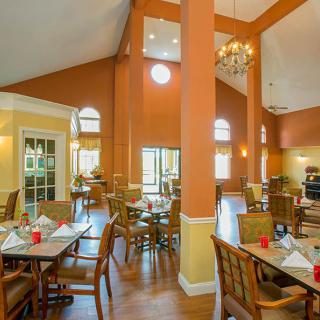 A spacious dining area with elegant decor, featuring tables and chairs arranged neatly under warm lighting.