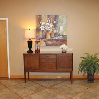 A stylish interior featuring a wooden console table, a decorative lamp, and vibrant artwork on the wall.