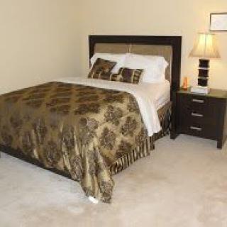 A cozy bedroom with a neatly made bed and nightstand.