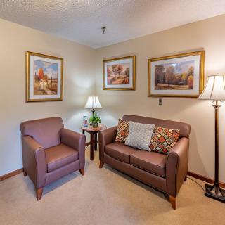 A cozy living room corner with a couch, armchair, and decorative lamps.