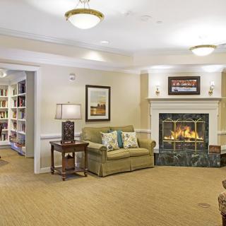 A cozy living room featuring a fireplace, sofa, and bookshelf.