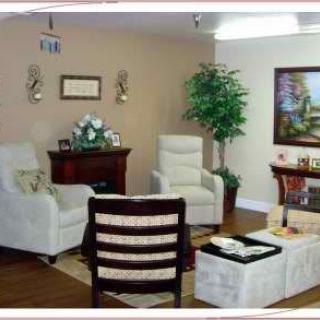 A cozy living room with armchairs, artwork, and decorative plants.