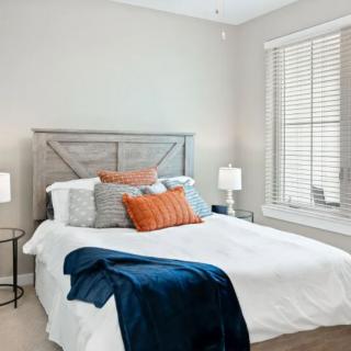 A cozy and stylish bedroom with a well-made bed, decorative pillows, and soft lighting.