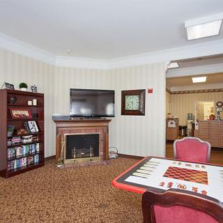 A cozy living room with a fireplace, TV, bookshelf, and a game table.