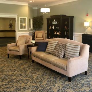 A cozy living room with a light-colored sofa and armchairs, complemented by decorative cushions and soft lighting.