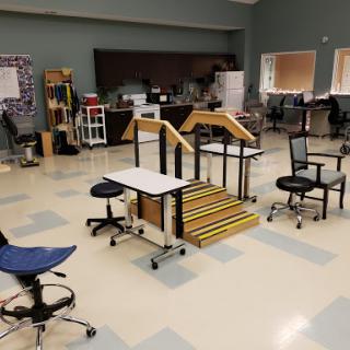 An organized classroom setting featuring various types of furniture including chairs and desks, along with a set of stairs for educational activities.