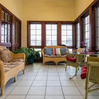 A cozy sunroom with wicker furniture, featuring comfortable seating and large windows allowing natural light to pour in.