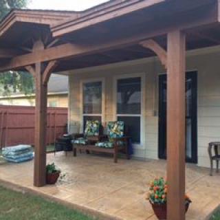 A cozy patio with wooden posts, outdoor seating, and potted plants.