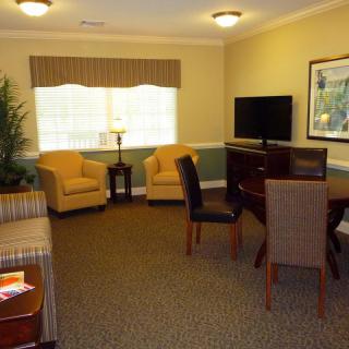 A cozy living room with comfortable seating, a television, and a table surrounded by chairs.