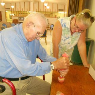 An elderly man and a woman engaging in an activity together indoors.