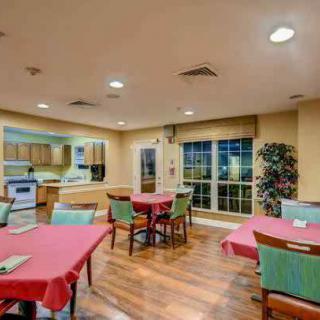 A cozy dining area with red tablecloths and a kitchen space in the background.