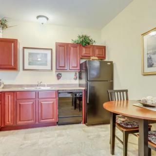 A compact kitchen and dining area featuring red cabinets, a refrigerator, and a small table with chairs.