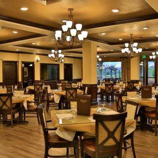 An elegant restaurant interior with neatly arranged tables and chairs, showcasing warm lighting.
