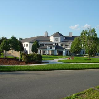 A large suburban house with a well-maintained lawn and surrounding trees.