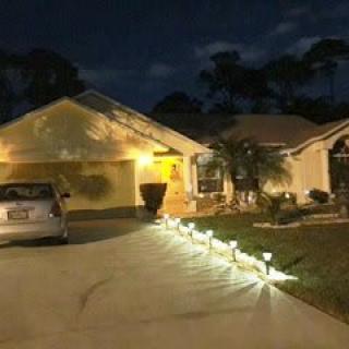 A suburban house illuminated at night with pathway lights leading up to the entrance.