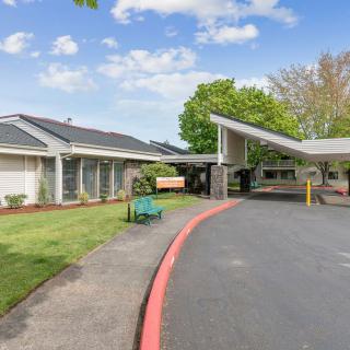 A building entrance with a driveway and landscaped surroundings on a clear day.