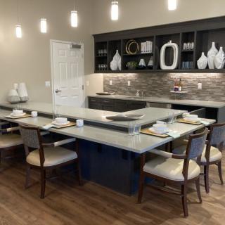 A modern kitchen with a large island and dining area, featuring elegant table settings and contemporary decor.
