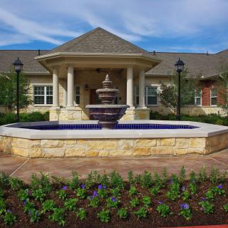 A serene garden with a central fountain in front of a beautiful building.