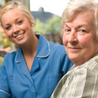 A healthcare worker assisting an elderly woman in a home setting.