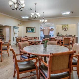 A spacious dining room with wooden tables and chairs, elegantly lit by chandeliers.