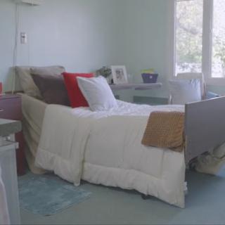 A cozy hospital room featuring a neatly made bed with soft bedding and a calming color palette.