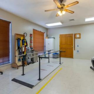 A rehabilitation room with parallel bars and exercise equipment for physical therapy.