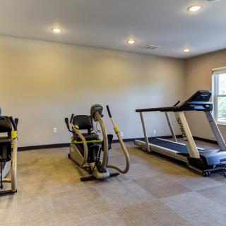A small gym with exercise equipment including a treadmill and an elliptical machine.