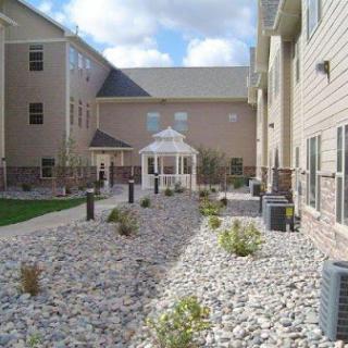 A serene courtyard featuring a gazebo surrounded by landscaped rocky areas and modern buildings.