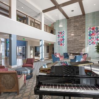 A modern lobby with a grand piano, comfortable seating, and colorful artworks.