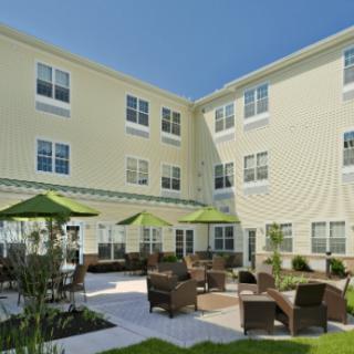 A view of a building with a courtyard featuring outdoor seating and umbrellas.