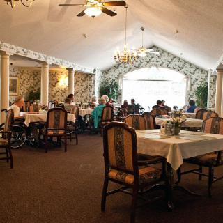 A cozy restaurant interior with tables set for dining, featuring elegant chandeliers and a relaxed atmosphere.
