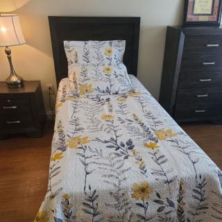 A neatly made single bed with floral bedding in a cozy bedroom.