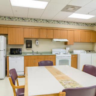 A spacious and well-equipped kitchen area featuring wooden cabinets, appliances, and a dining table.