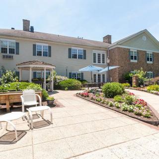 A beautifully landscaped patio area with chairs and umbrellas in front of a building.