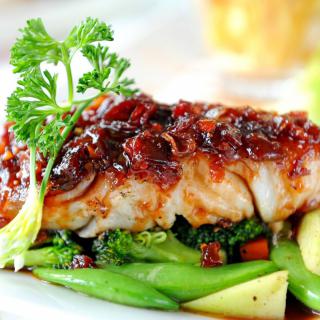 A gourmet fish dish garnished with herbs and served on a bed of mixed vegetables.
