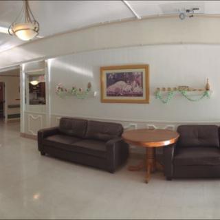 A cozy lobby area with two brown sofas, a round wooden table, and a framed artwork on the wall.