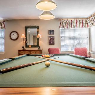 A cozy billiard room with a well-kept pool table and comfortable seating.