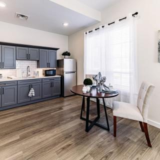 A modern kitchen-dining area with grey cabinets, hardwood floors, and ample natural light.