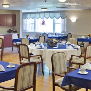 A neatly arranged dining area with multiple tables and chairs, decorated with blue tablecloths and white napkins.