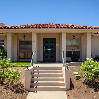A charming house with a front entrance featuring steps and a small garden under a clear blue sky.
