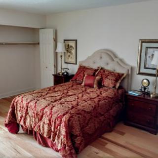 A cozy bedroom featuring a nicely made bed with ornate bedding, complemented by decorative artwork and lamps.
