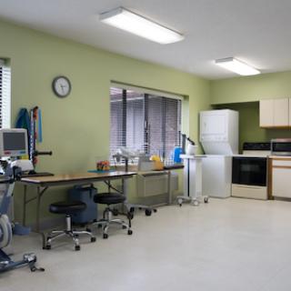 A functional rehabilitation clinic featuring exercise equipment and a kitchenette.