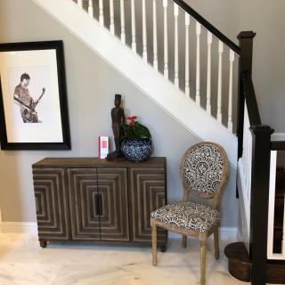 Stylish interior featuring a modern staircase with a decorative cabinet and patterned chair.
