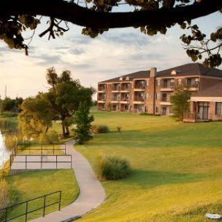 A scenic view of a lakeside building surrounded by lush greenery and a peaceful path.