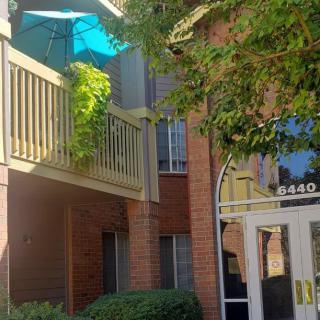 An apartment building with a balcony featuring an umbrella and plants.