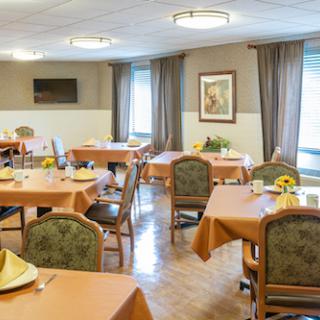 A cozy dining area set for a meal, featuring orange tablecloths and inviting decor.