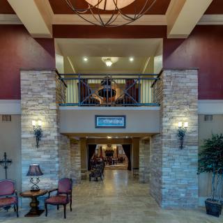 A hotel lobby featuring elegant interior design with stone pillars and a large chandelier.